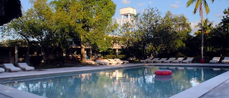 A swimming pool with lounge chairs and a water tower in the background.