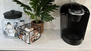 Eine Küchenarbeitsplatte mit einer Kaffeemaschine, einem Topfpflanzen, einem Gewürzregal und einem Gewürzglas.