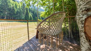 A hammock chair on a wooden deck with a view of a fenced field and forest. - Perched hut La Résilience, on the Vercors plateau (Autrans-Méaudre en Vercors)