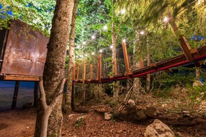 Un puente de madera en un área boscosa con luces colgantes.