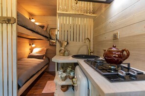 Una cocina compacta con estufa a gas, lavamanos y armarios de madera.