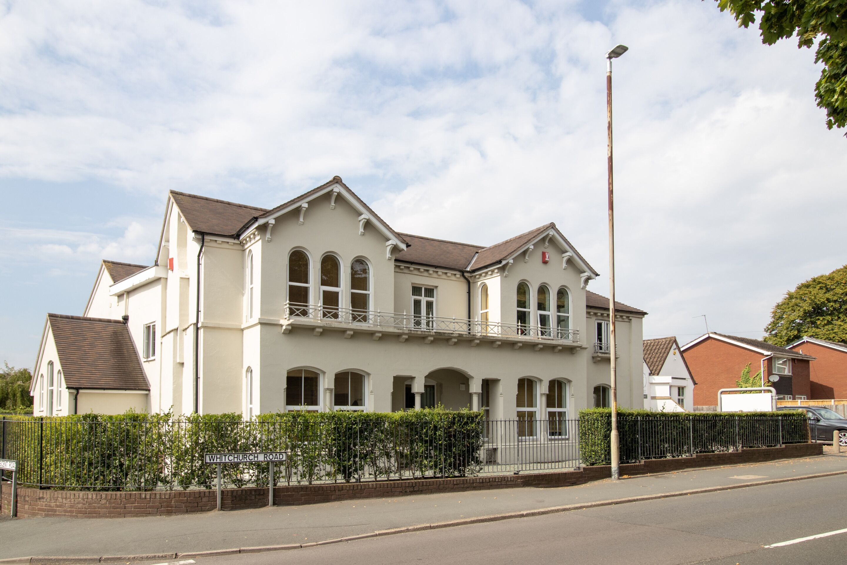 A two-story building with a symmetrical facade, multiple windows, and a balcony.