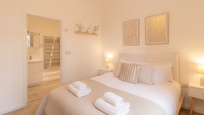 Een keurig opgemaakt slaapkamer met een bed, nachtkastjes en een nachtkastje.