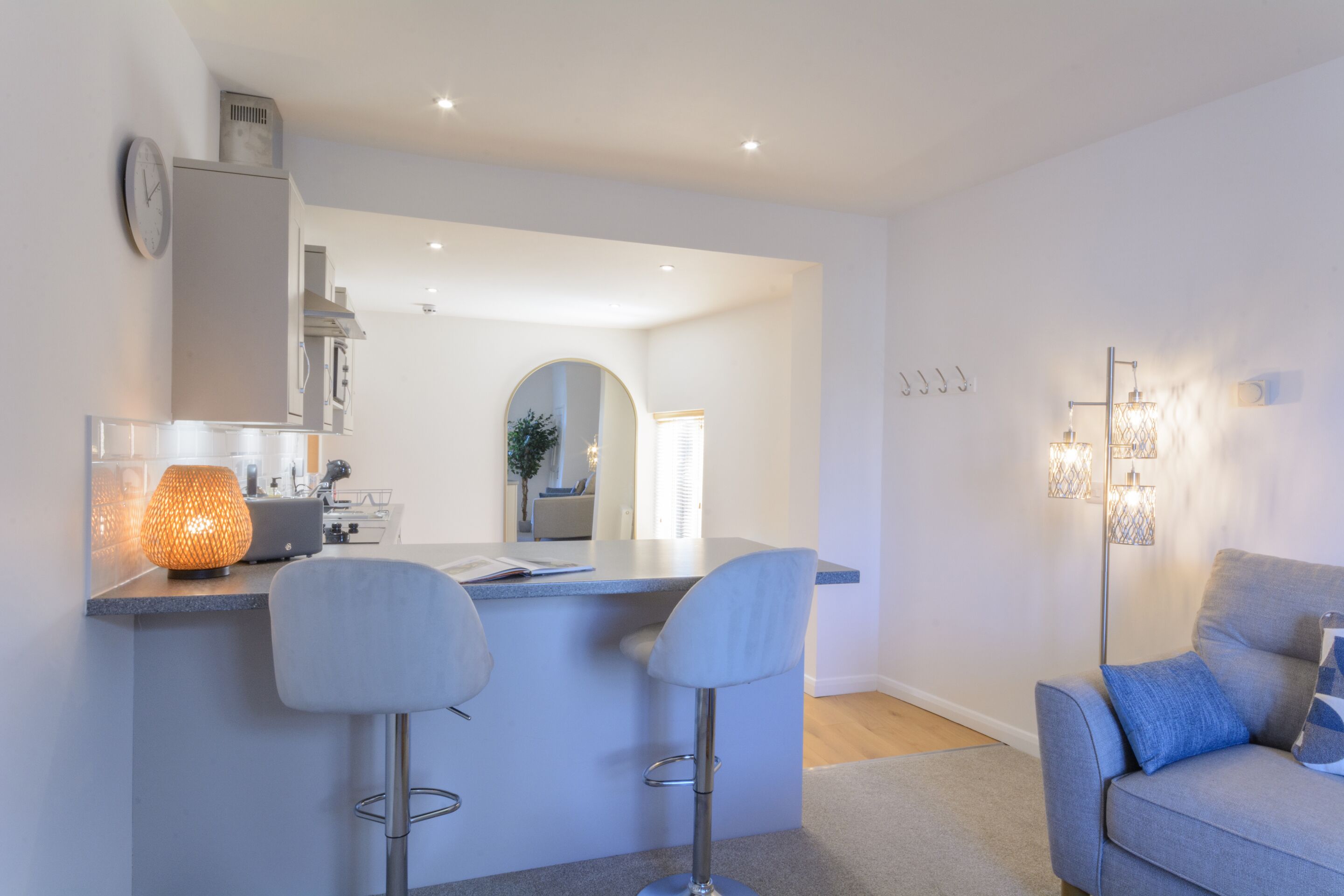 A modern kitchen with a bar area, a dining table, and a sofa.