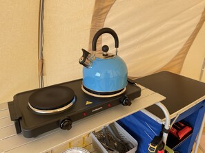 A portable electric kettle on a portable stove, with a control panel and a safety lock.