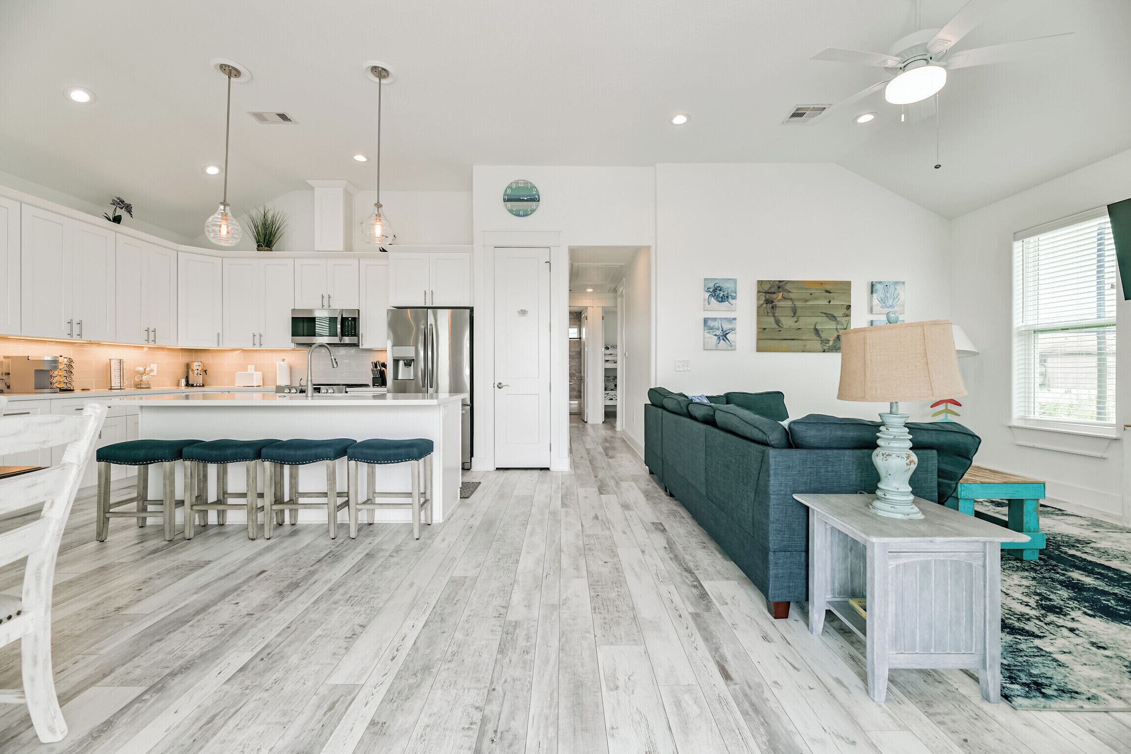 A modern kitchen with white cabinetry, a central island, and bar stools.