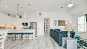 Een moderne keuken met witte kasten, een centraal eiland en barstoelen.