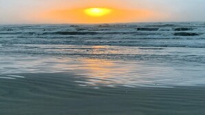 Een strand met golven en een zonsondergang.