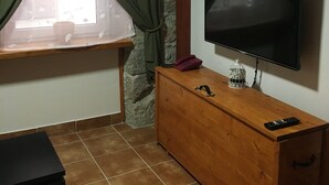 A room with a window, curtains, a wooden TV stand, a television, a telephone, a remote control, and a stack of black boxes. - Apartment Equinox-Island Pag (Pag)