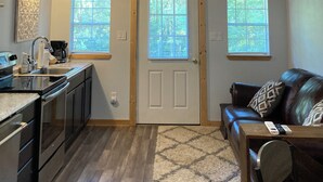 A cozy interior with a kitchen, a living area with a couch, and a ceiling fan. - Cana Cottage | Farm Stay (Tyler)