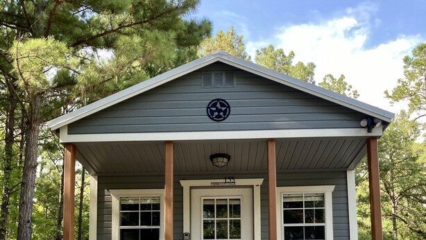 A small cabin with a front porch, a door, and a window. - Cana Cottage | Farm Stay (Tyler)
