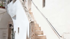 A white building with a stone staircase leading to an upper level.