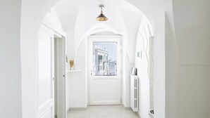 A white hallway with a door leading to a city view, a radiator, and a pendant light.