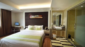 Ein Hotelzimmer mit Bett, Schreibtisch, Computer, Badezimmer und einer Rezeption.