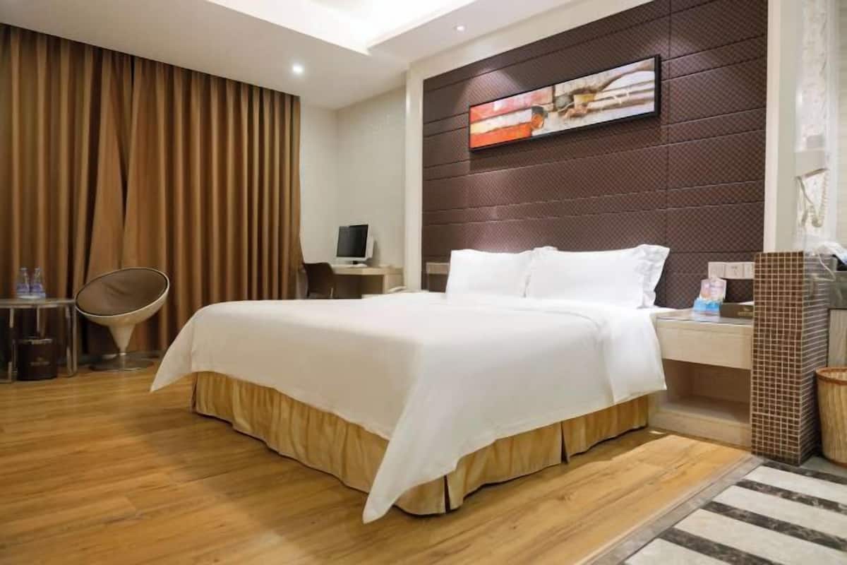 Une chambre d’hôtel équipée d’un lit, d’un bureau, d’une chaise, d’une télévision et d’une œuvre d’art accrochée au mur.