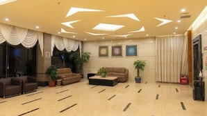 Eine großzügige Lobby mit modernem Deckenstil, einer Sitzecke mit Sofas und einem Couchtisch sowie Zimmerpflanzen.