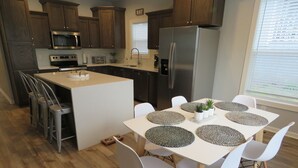 Uma cozinha moderna com uma ilha central, cadeiras brancas e uma mesa de jantar com jogos americanos.