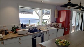 A kitchen with a view of the ocean, a red refrigerator, and a bowl of fruit on the counter. - Charming town with panoramic views and swimming pool (Saint-Leu)