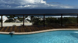 A clear blue sky with clouds, a wooden deck, and a swimming pool. - Charming town with panoramic views and swimming pool (Saint-Leu)