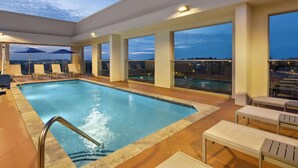 A rooftop pool area with a view of the city at dusk, including lounge chairs and umbrellas. - Hilton Garden Inn Nashville West End Avenue (Nashville)