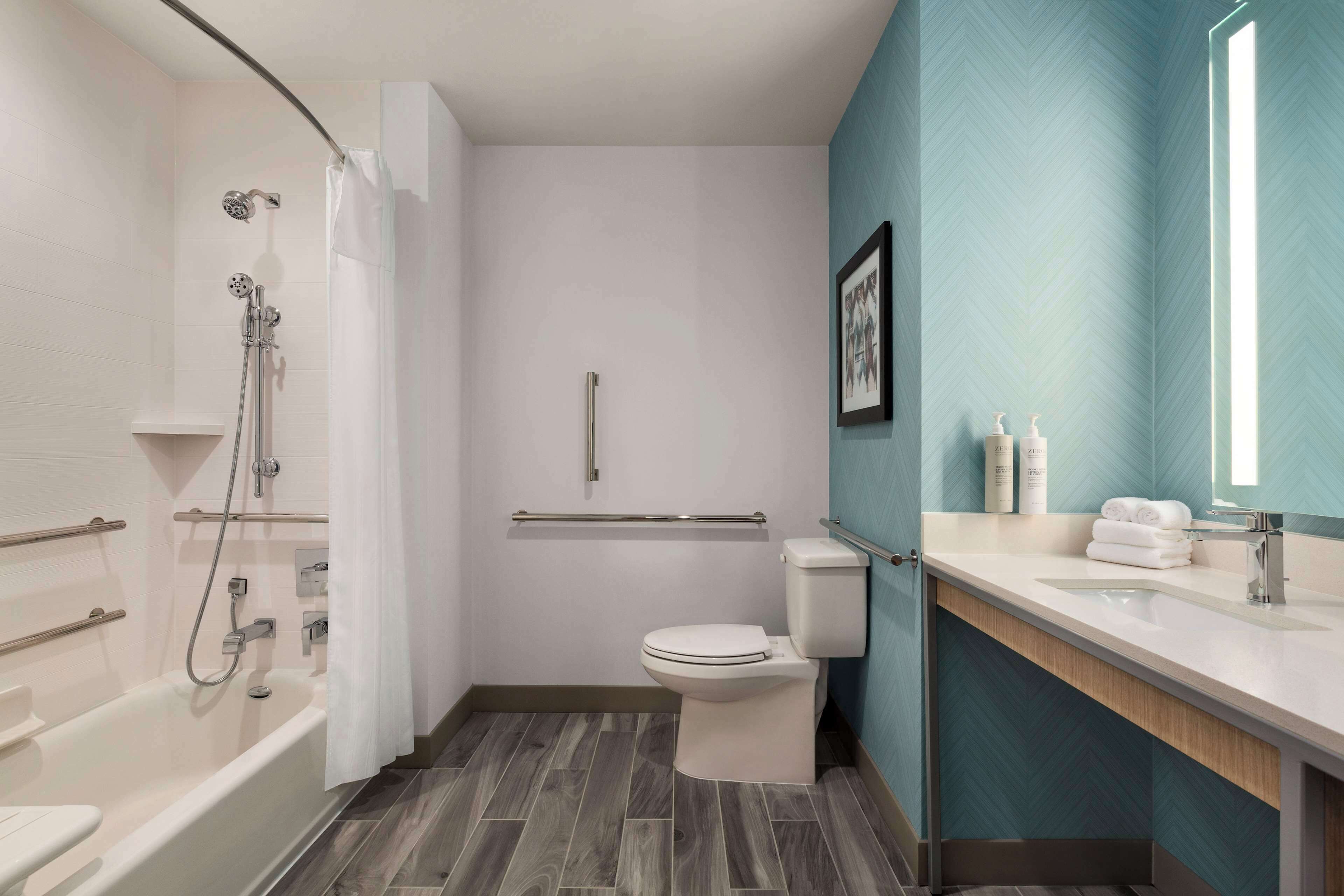 Un baño moderno con bañera, ducha, inodoro y tocador con lavabo y espejo.