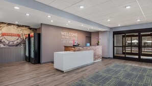 A reception area with a modern design, including a reception desk, a wall with a 'Welcome to the Sun Set Station' sign, and a view through the glass doors. - Hampton Inn Williams (Williams)