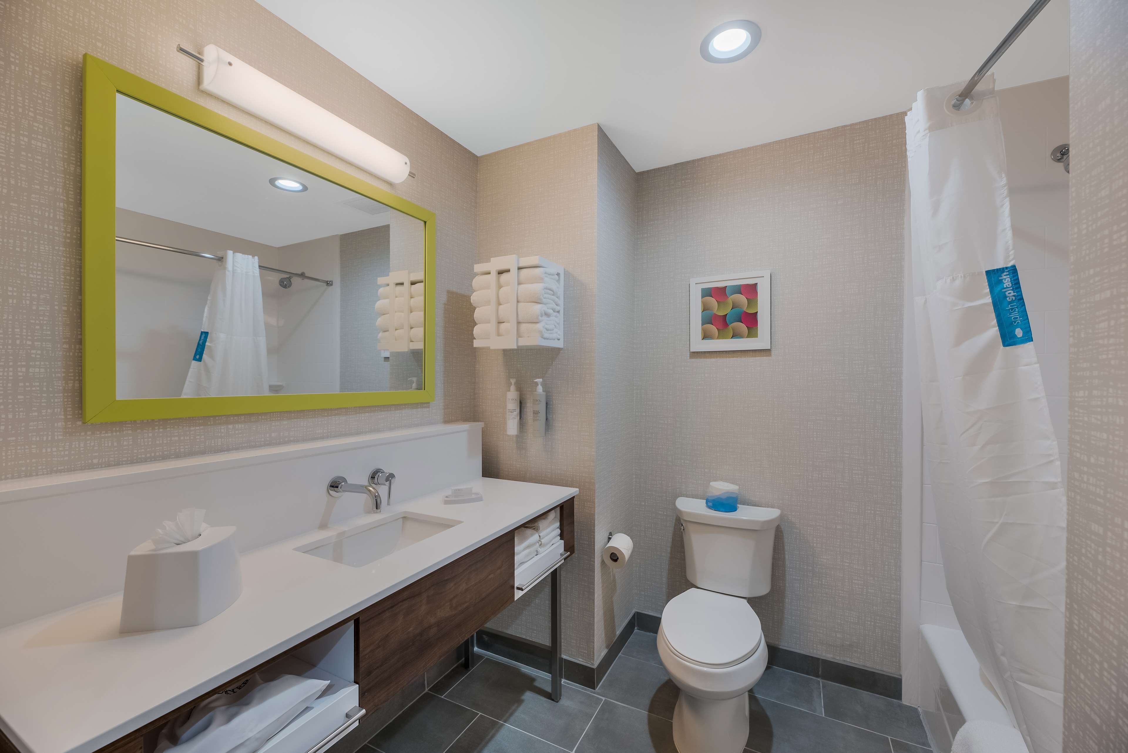 Un baño moderno con un espejo grande, dos lavamanos, un inodoro y una cortina de ducha.