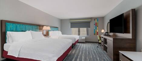 A hotel room with a large bed, a desk, a TV, and a window with a view.
