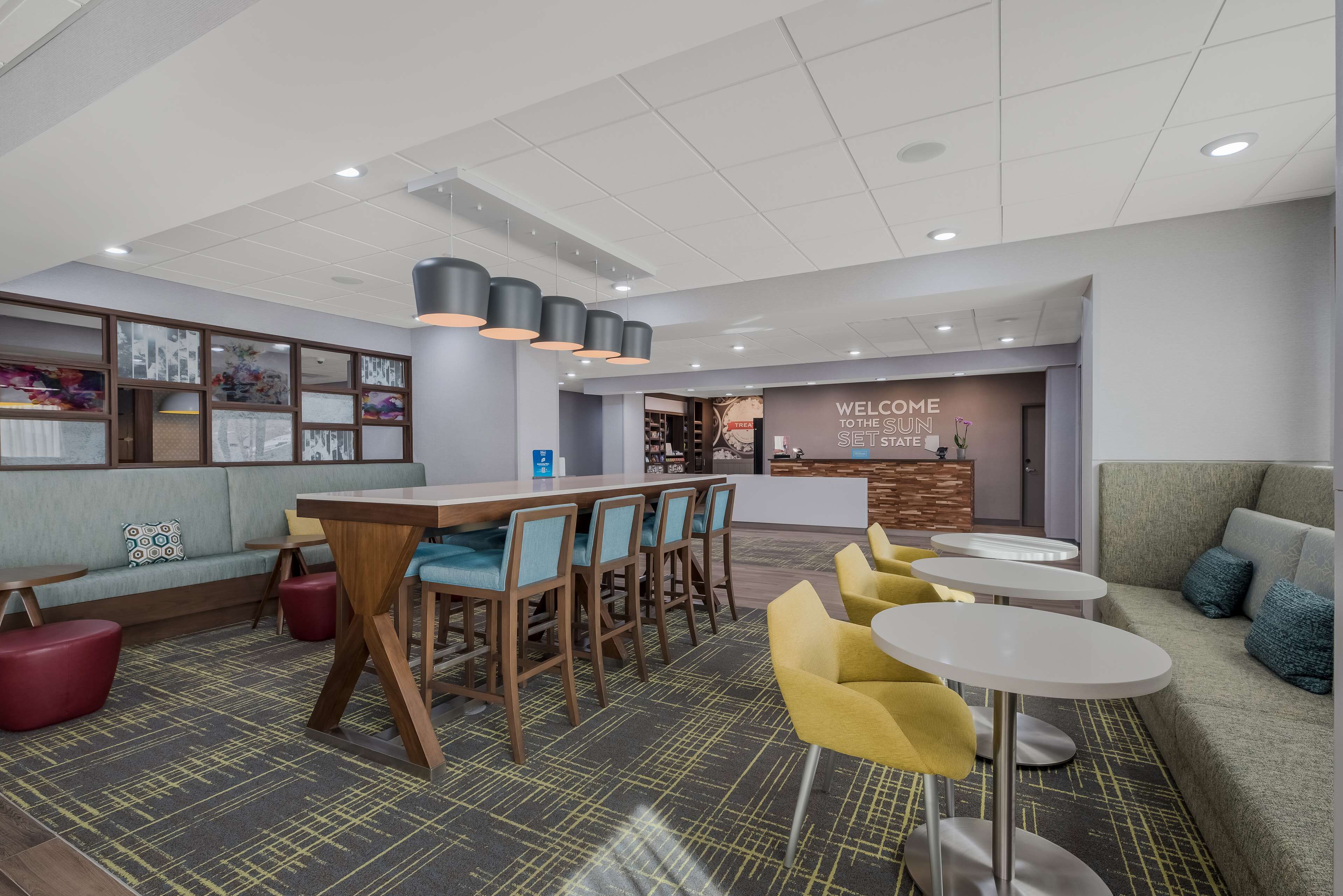 Un área de lounge moderna con barra, asientos y una recepción.