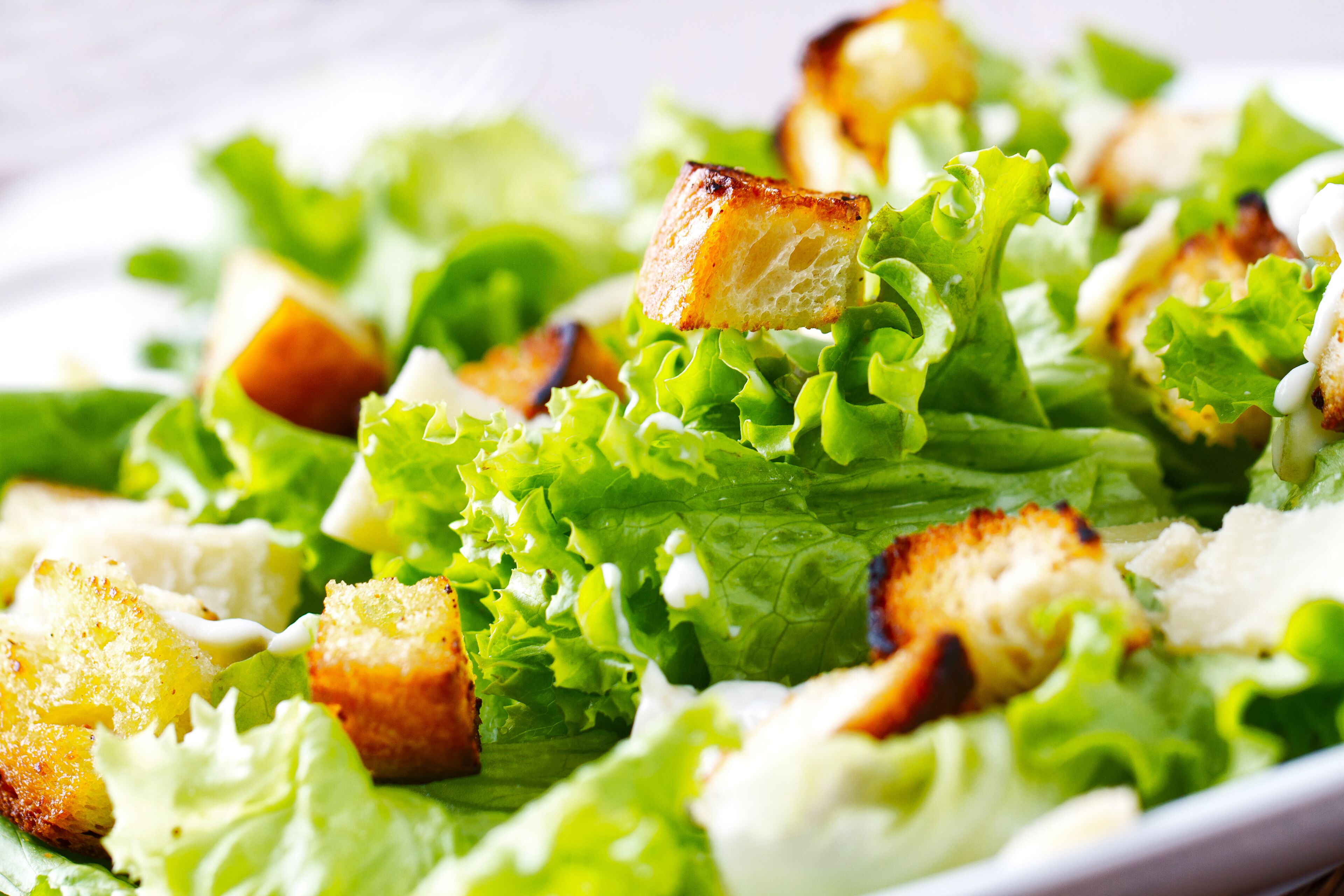A close-up of a salad with croutons and lettuce.