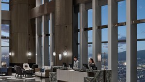 A modern hotel lobby with a reception desk, seating area, and large windows offering city views. - Hilton Zhuji (Shaoxing)