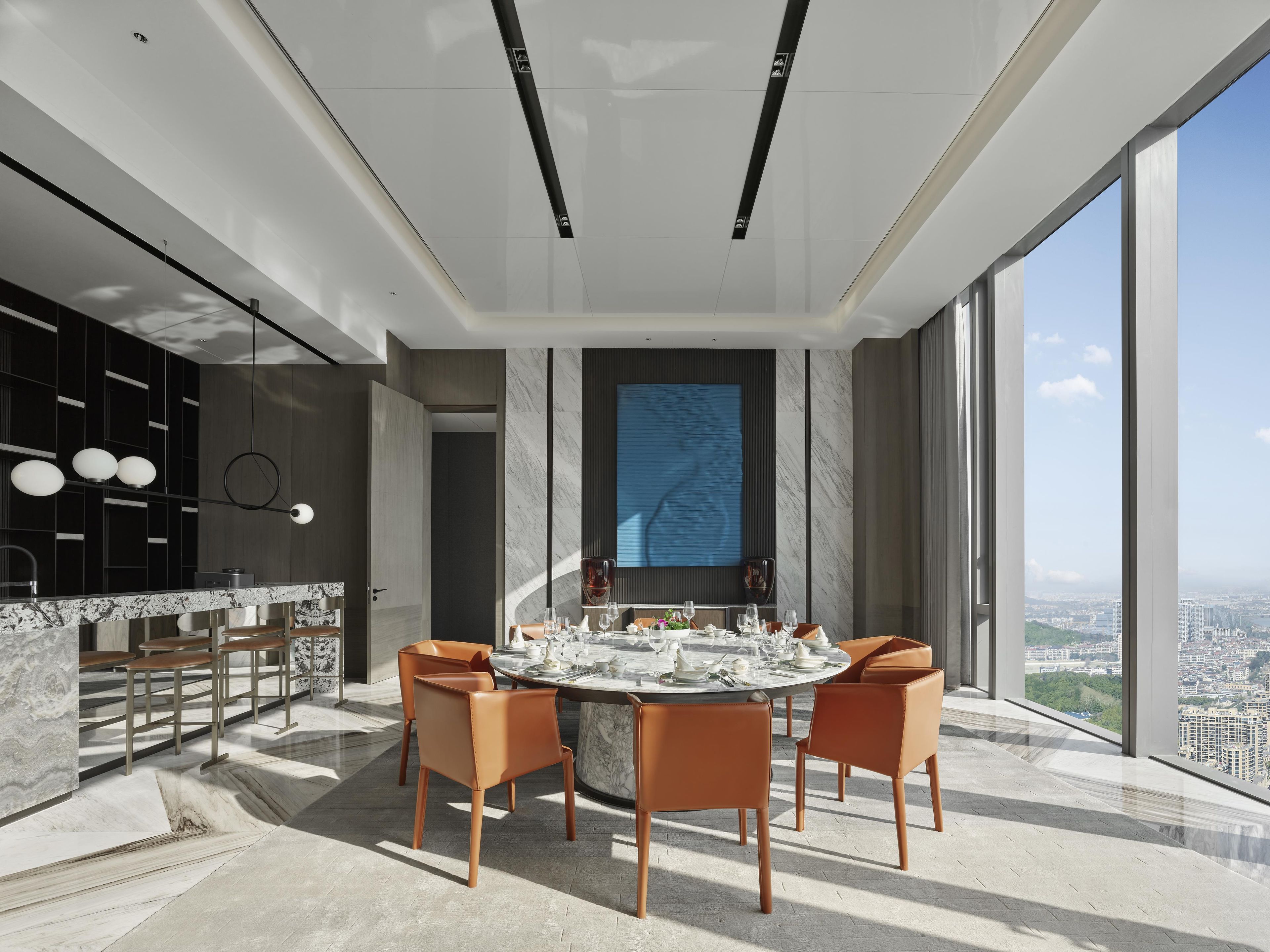 A modern dining area with a round table, four chairs, and a city view.