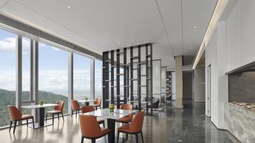 A modern dining area with large windows, a marble floor, and a high ceiling.