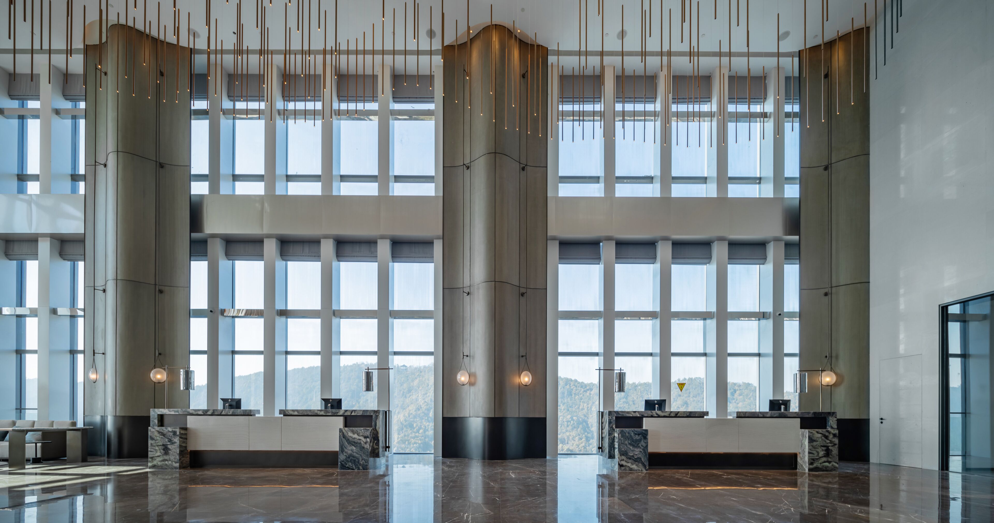 A spacious lobby with large windows, a central column, and a reception desk.
