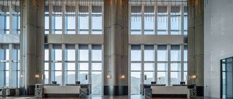 A spacious lobby with large windows, a central column, and a reception desk.