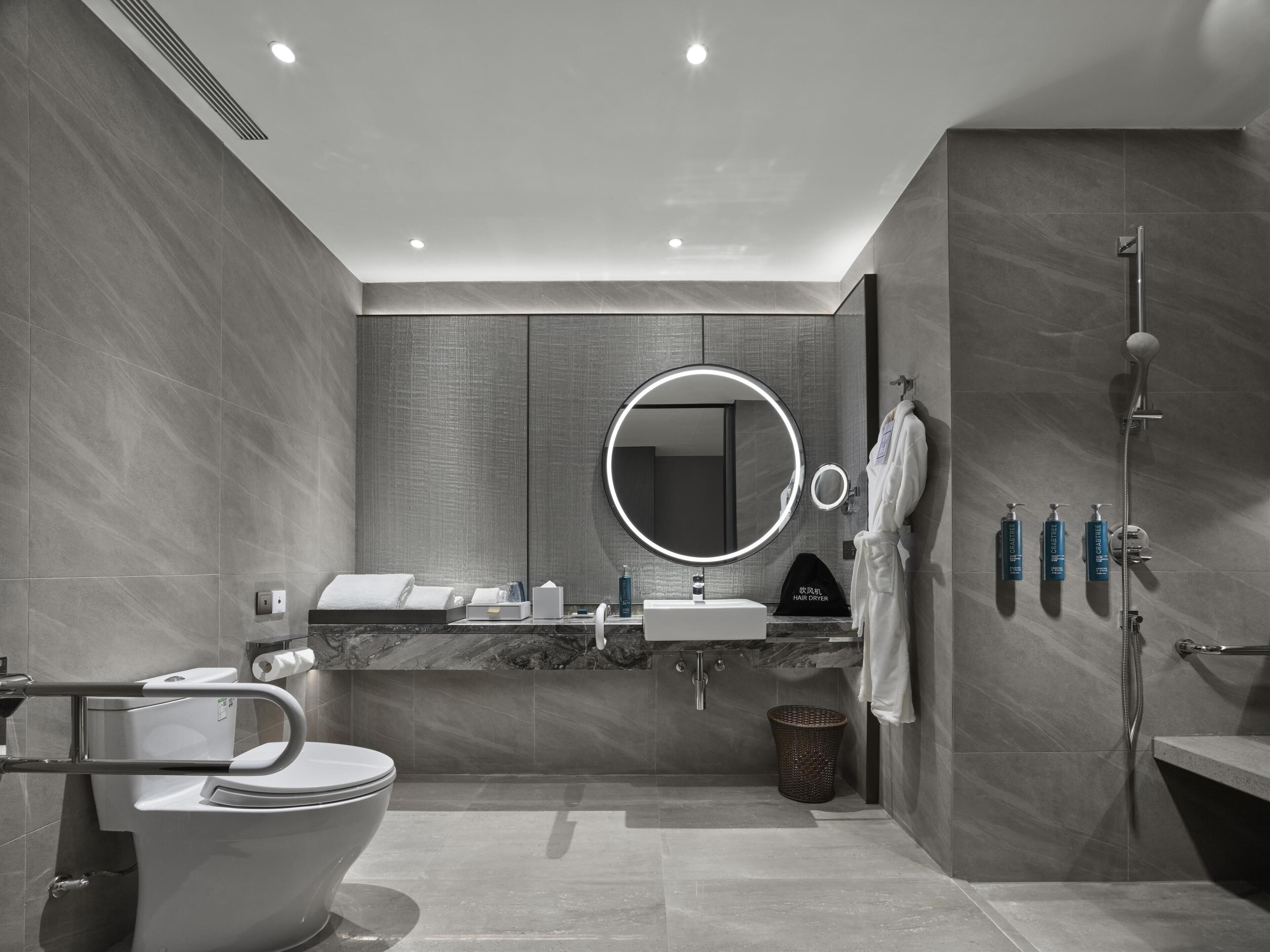 Ein modernes Badezimmer mit Toilette, Waschbecken, Spiegel und Dusche.