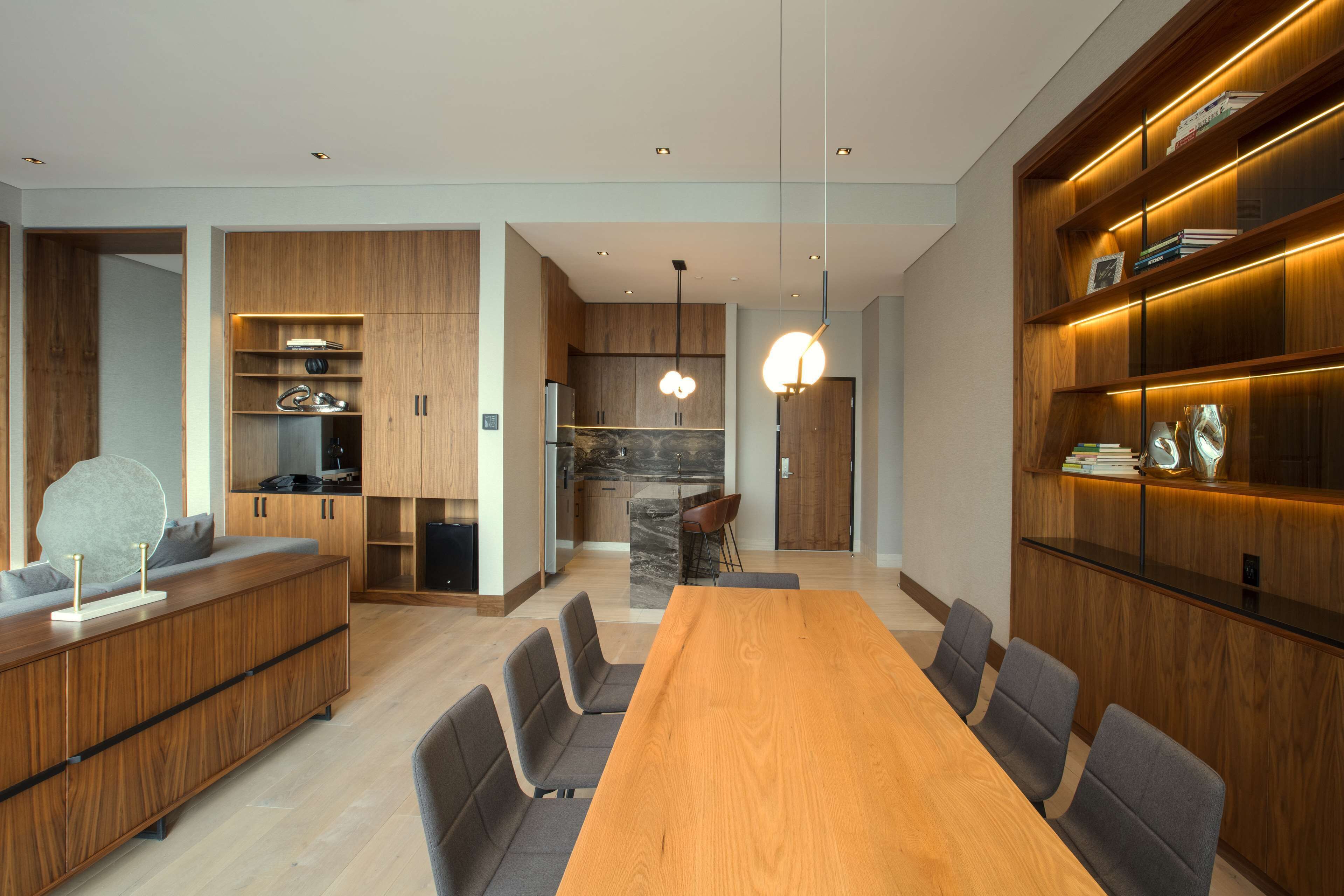 Una cocina moderna con armarios de madera, una isla de mármol e iluminación colgante.