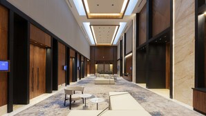 A modern hotel lobby with a long corridor, seating areas, and a reception desk.