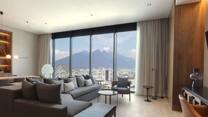 A modern living room with a large window, a sofa, a coffee table, and a bookshelf. - Hilton Monterrey Valle (Monterrey)
