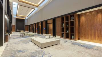 A spacious lobby with a high ceiling, recessed lighting, and a large seating area.