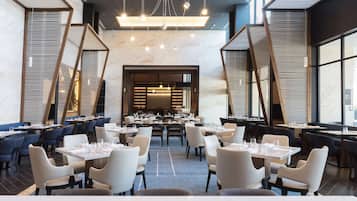 Un restaurante espacioso con varias mesas y sillas, suelo de mármol y un diseño interior moderno.