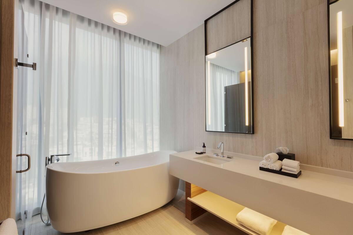 A modern bathroom with a freestanding bathtub, a vanity with a mirror, and a towel rack.
