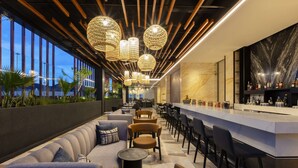 A modern lounge area with seating, a bar, and decorative lighting. - Hilton Monterrey Valle (Monterrey)