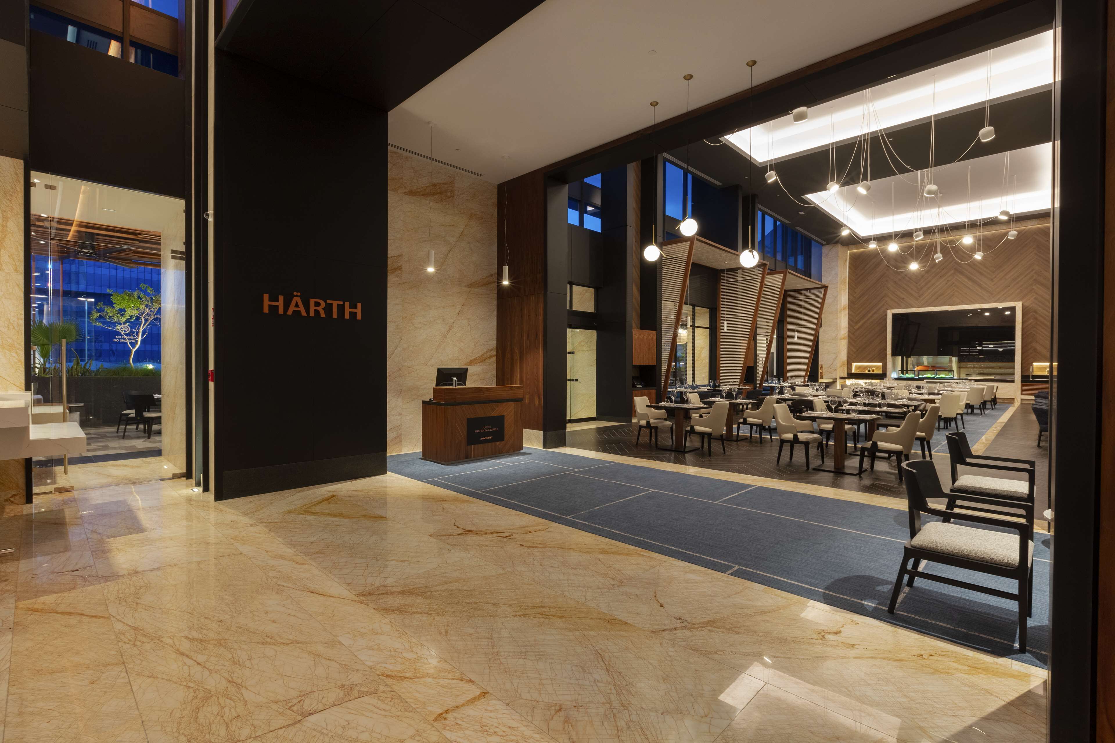 Un hall d’hôtel moderne doté d’un comptoir d’accueil, d’un espace salon et d’une grande fenêtre offrant une vue sur l’extérieur.