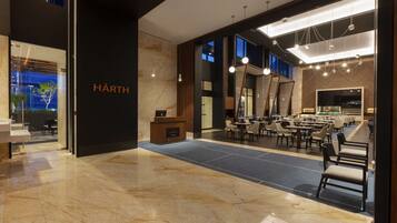Un hall d’hôtel moderne doté d’un comptoir d’accueil, d’un espace salon et d’une grande fenêtre offrant une vue sur l’extérieur.