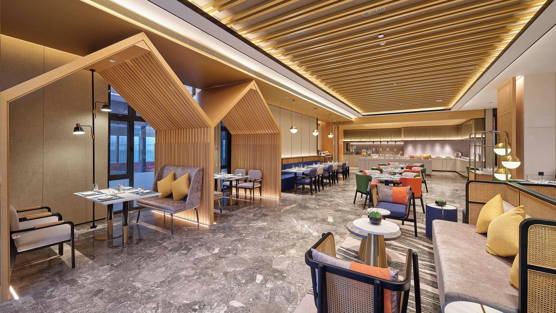 A modern hotel lobby with a mix of seating areas, a central bar, and a kitchen visible in the background.