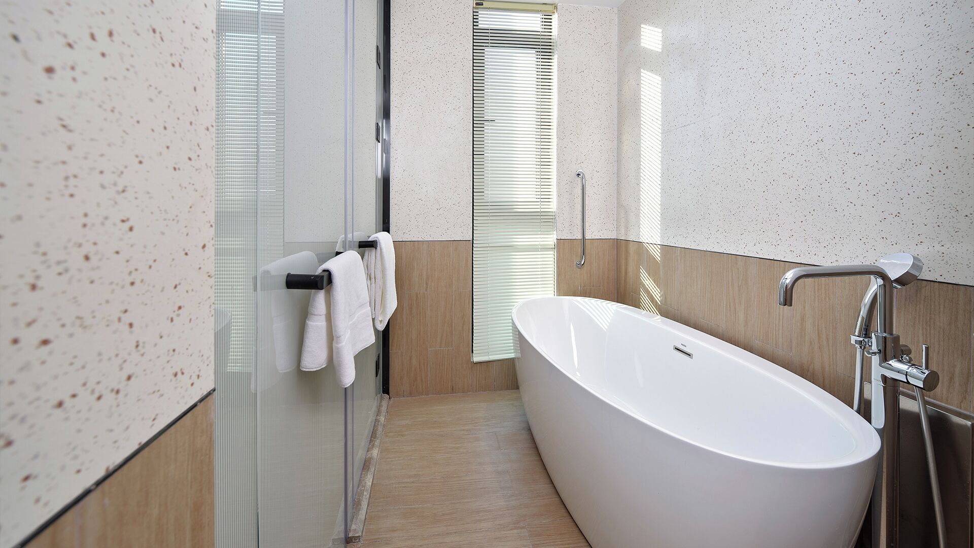 Un baño moderno con una bañera independiente, un box de ducha de vidrio y suelo de madera.