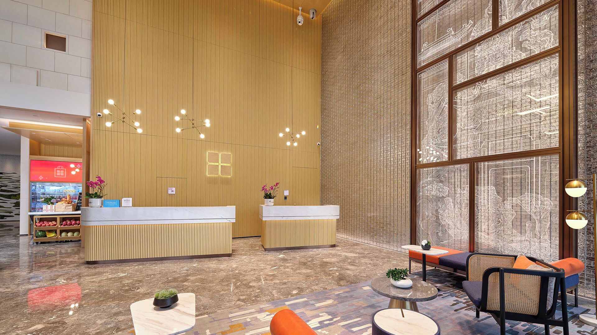 A hotel lobby with a reception desk, seating area, and large windows.