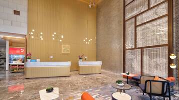 A hotel lobby with a reception desk, seating area, and large windows.
