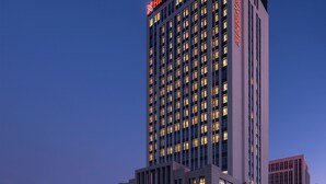 A tall, modern hotel building with illuminated signage at the top and a prominent entrance at the base. - Hilton Garden Inn Liaocheng Jiangbei Shuicheng (Liaocheng)